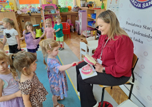 Marianka czyści zęby na pokazowej sztucznej szczęce.