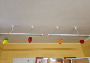 Z lamp zwisają papierowe jesienne owoce.