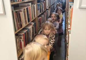Dzieci stworzyły pociąg i zwiedzają bibliotekę.