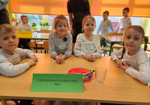 Szymon, Oliwia, Wiktoria i Zuzia siedzą przy stoliku czekając za rozpoczęciem konkursu