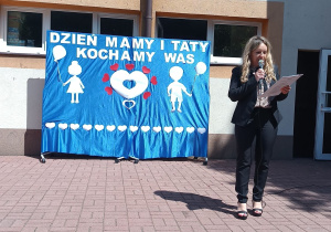 Pani Dyrektor stoi obok dekoracji i składa wszystkim rodzicom przedszkolaków serdeczne życzenia.