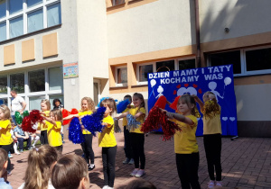 Przedszkolaki w tańcu machają pomponami.