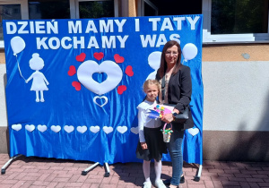 Wiktoria z mamą stoi na tle dekoracji.