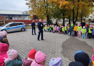 Przedszkolaki słuchają o zasadach bezpieczeństwa na drodze.