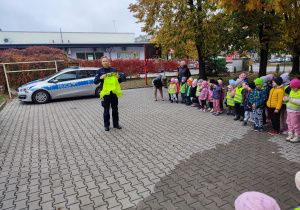 Policjant pokazuje kamizelkę odblaskową.