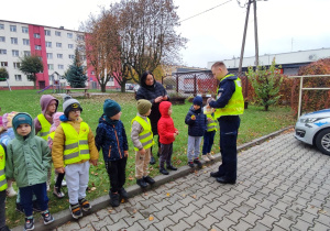 Policjant rozdaje dzieciom odblaski.
