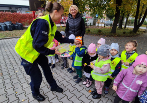 Policjantka rozdaje ,,Biedronkom” odblaski.
