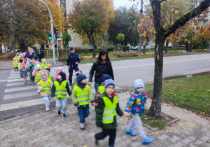 Dzieci przechodzą po pasach na skrzyżowaniu z sygnalizacją świetlną.