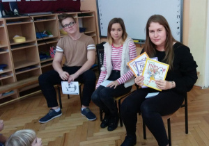 Uczennica Julia prezentuje dzieciom książki, które zostały podarowane do przedszkolnej biblioteki.