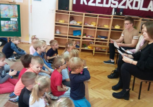 Dzieci siedzą naprzeciwko uczniów i słuchają czytanego opowiadania.