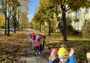 Grupa „Słoneczek” idzie parami osiedlową alejką.
