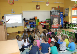 Przedszkolaki oglądają na tablicy interaktywnej zdjęcia przejazdów kolejowych.