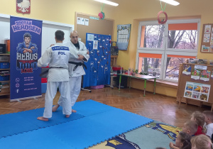 Sportowcy walczą ze sobą na macie.