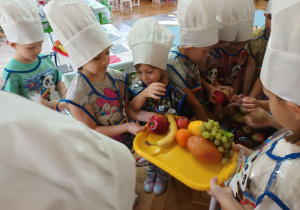 Emilka i Lilia trzymają tacę, na którą dzieci odkładają umyte owoce.