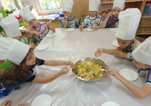 Maja i Franek doprawiają sałatkę odrobiną miodu.