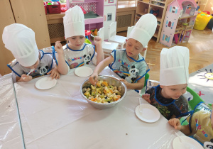 Antek K. miesza składniki sałatki owocowej.