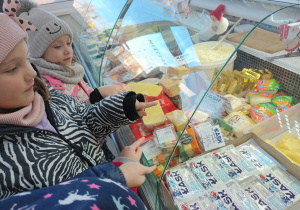 Emilka, Lilia i Hania pokazują sery żółte i białe.