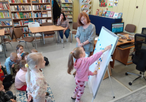 Grupa obserwuje Oliwkę, uzupełniającą puzzle na tablicy.