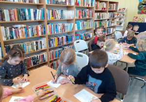 Dzieci przy stolikach kolorują obrazki.