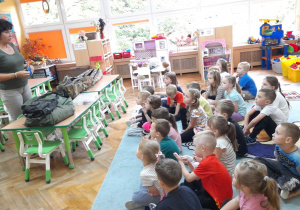 Dzieci siedzą na dywanie i z uwagą słuchają opowieści Pani Renaty.