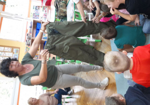 Pani Renata pokazuje dzieciom spodnie wędkarskie.