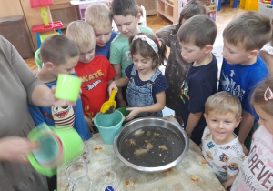 Maja dosypuje ziemię do wody.