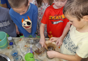 Jaś i Jakub trzymają filtr i obserwują przepływ wody.