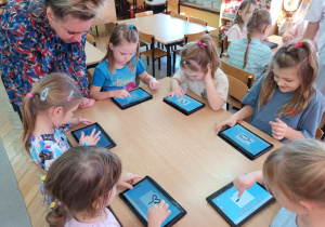 Pani Dyrektor obserwuje jak dziewczynki rysują na tablecie listki w 3D.