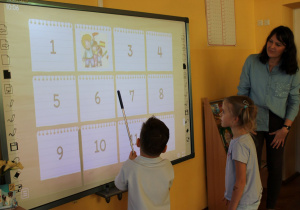 ,,Krasnoludki” wykonują zadanie przy tablicy multimedialnej.