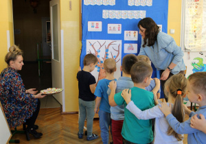Dzieci ustawione w rzędem, tworzą ,,drzewo” i częstują się cukierkiem.