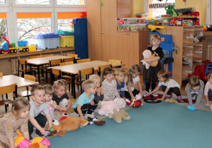 Dzieci kładą swoje misie na dywanie.