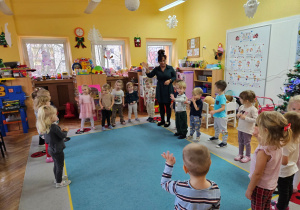 Dzieci wraz z panią Kamilką stoją w kole witając się piosenką