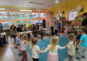 Dzieci wraz z panią Kamilką witają się w kole śpiewając piosenkę "Dzień dobry"