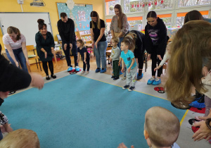 Rodzice wraz z dziećmi stoją w kole wykonując ćwiczenia