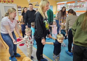 Rodzice wraz z dziećmi podczas zabawy ruchowej "Reniferowe zaprzęgi"