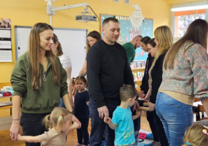 Rodzice wraz z dziećmi podczas zabawy ruchowej "Reniferowe zaprzęgi"