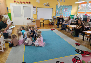 Pani Ania czyta bajkę o Świętym Mikołaju, dzieci i rodzice uważnie słuchają