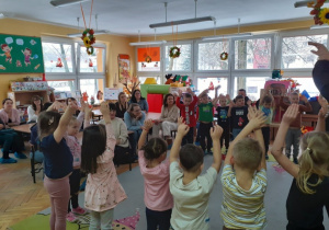 Przedszkolaki trzymają ręce w górze.