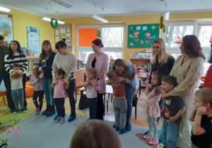 Rodzice wspólnie z dziećmi stoją w kole.