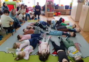Przedszkolaki relaksują się leżąc na dywanie.