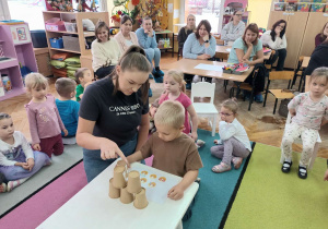 Alex z mamą układa piramidę z kubków.