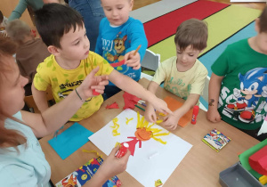 Chłopcy doklejają włosy z bibuły.