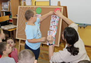 Fabian przepina obrazek do tablicy korkowej.