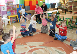 Dzieci tworzą z włóczki pajęczynę przyjaźni.