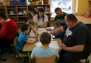 Chłopcy z rodzicami wykonują ilustrację do bajki.