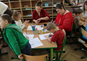 Mama Emmy i Szymona pomagają dzieciom w wykonaniu ilustacji.