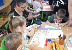 Franek kończy rysować, a Hania z mamą przygotowują obrazki do złożenia w książeczkę.