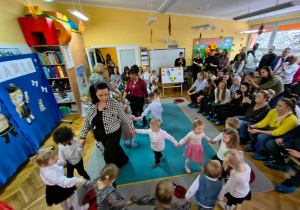 Dzieci z grupy "Biedronek" i "Żabek" wraz z paniami tańczą w trzech kółeczkach