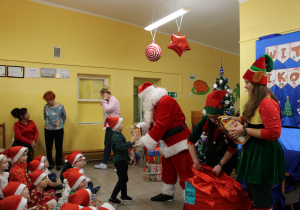Franek z grupy "Krasnoludki" odbiera prezent od Mikołaja