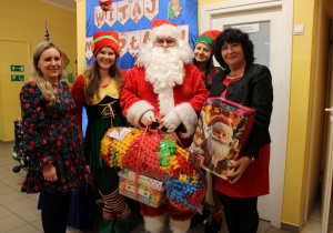 Wychowawczyni z grupy "Słoneczek" odbiera prezent do sali od Mikołaja